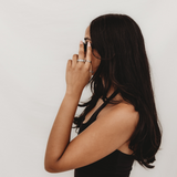 Woman with long dark hair wearing a black top against a white background