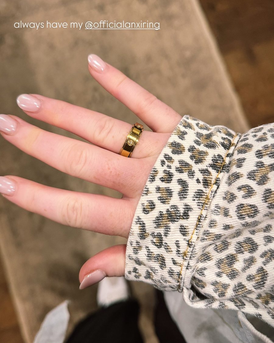 Hand with a gold Anxi Ring and a leopard print sleeve