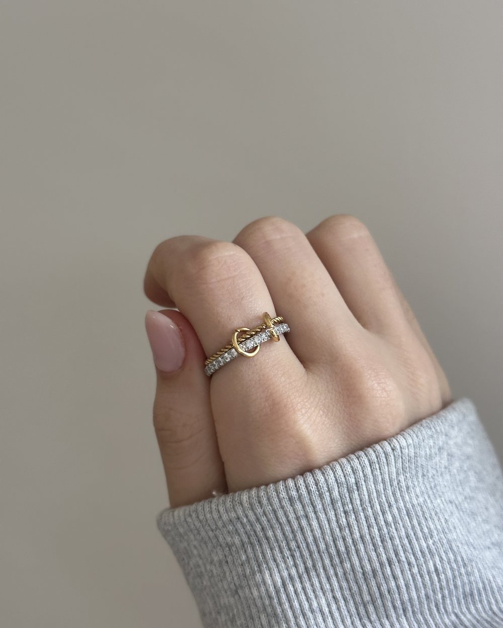 Gray knit sleeve, gold Anxi Rings on a silver tray