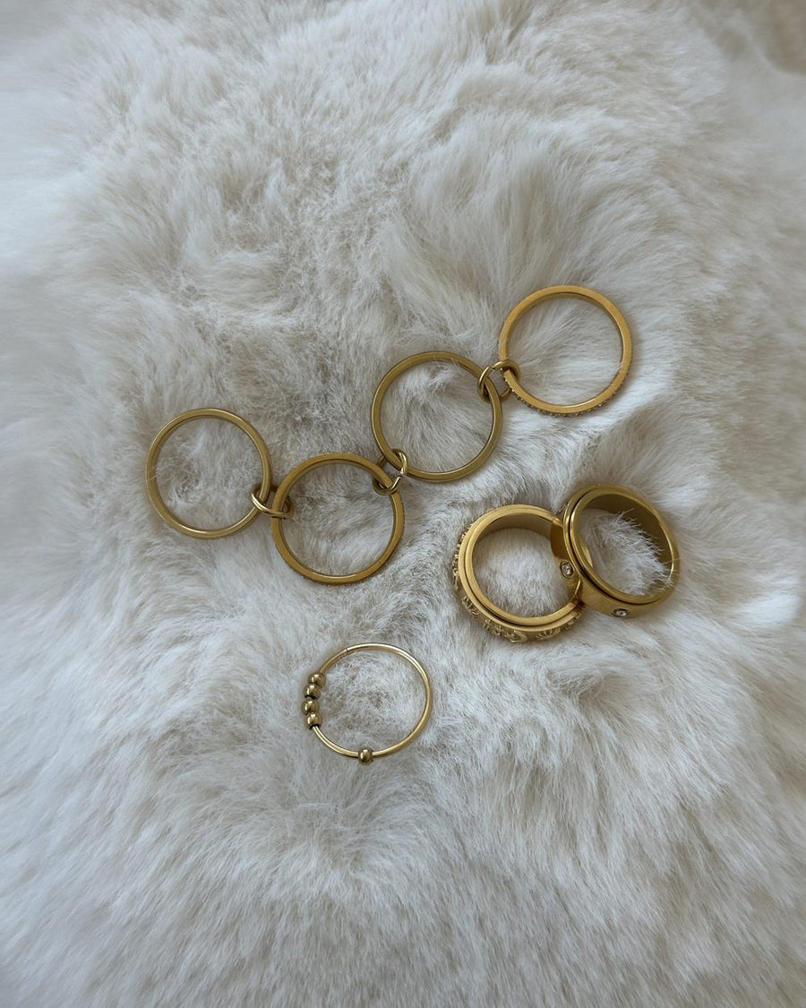 A scatter of gold Anxi Rings on soft white faux fur