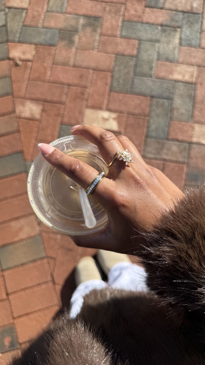 Hand with Anxi Rings and a fur coat holding an iced coffee