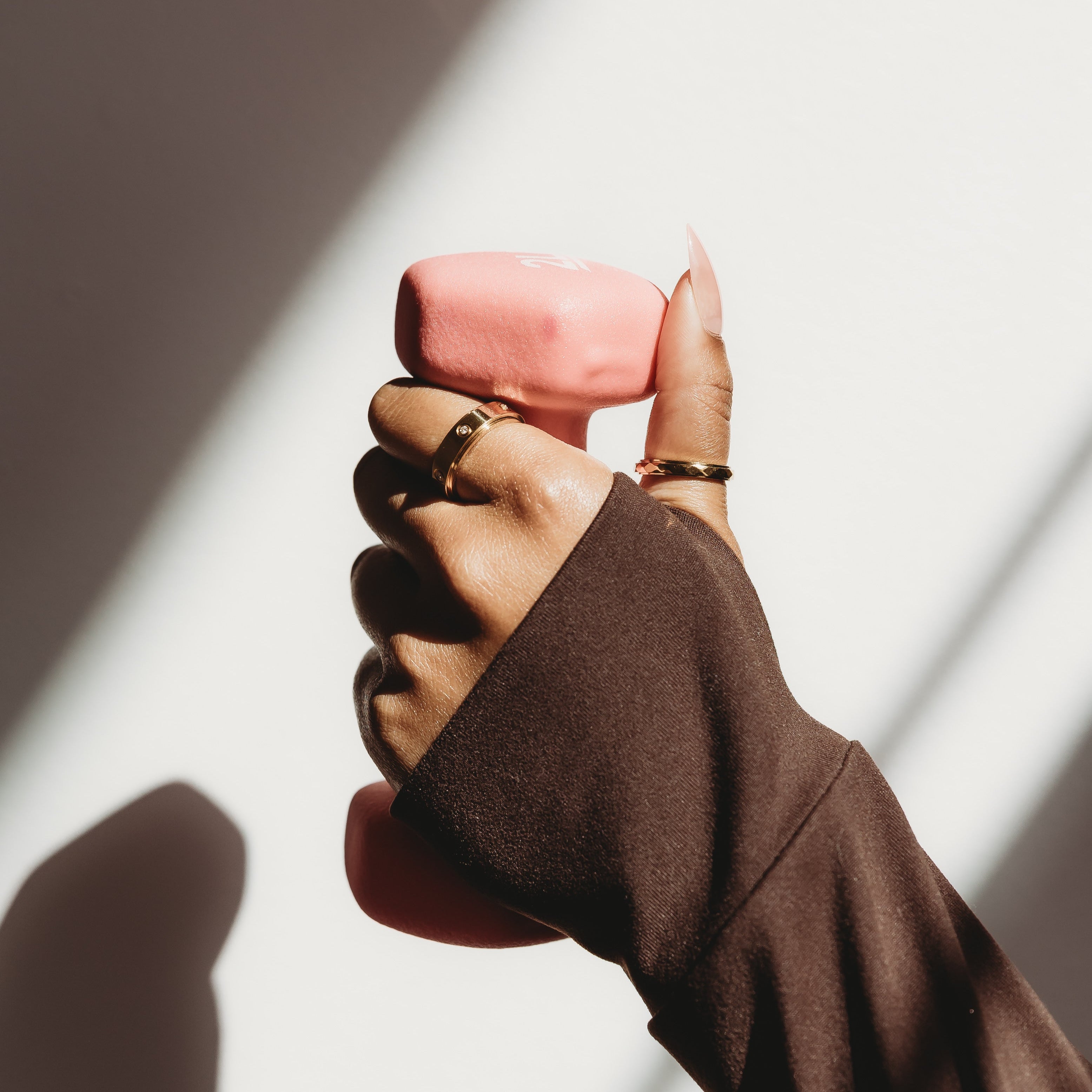 Hand holding a pink object with a blurred background