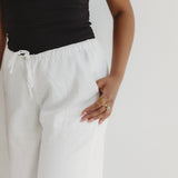 Person wearing white pants and a black top on a plain background