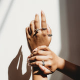 Two hands with rings on a light background