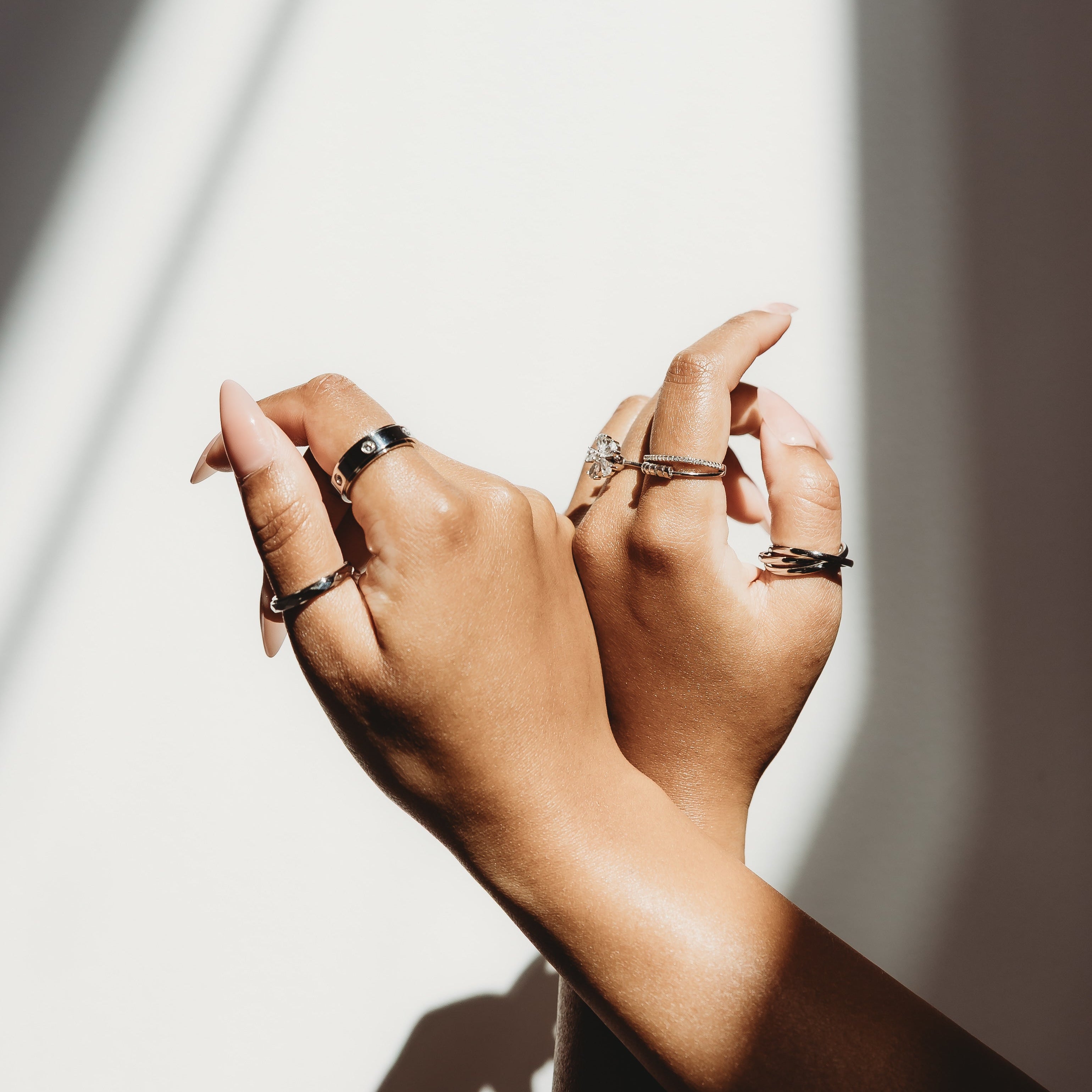 Close-up of a hand with multiple rings on a light background