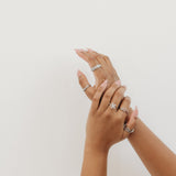 Two hands with multiple rings on a light background
