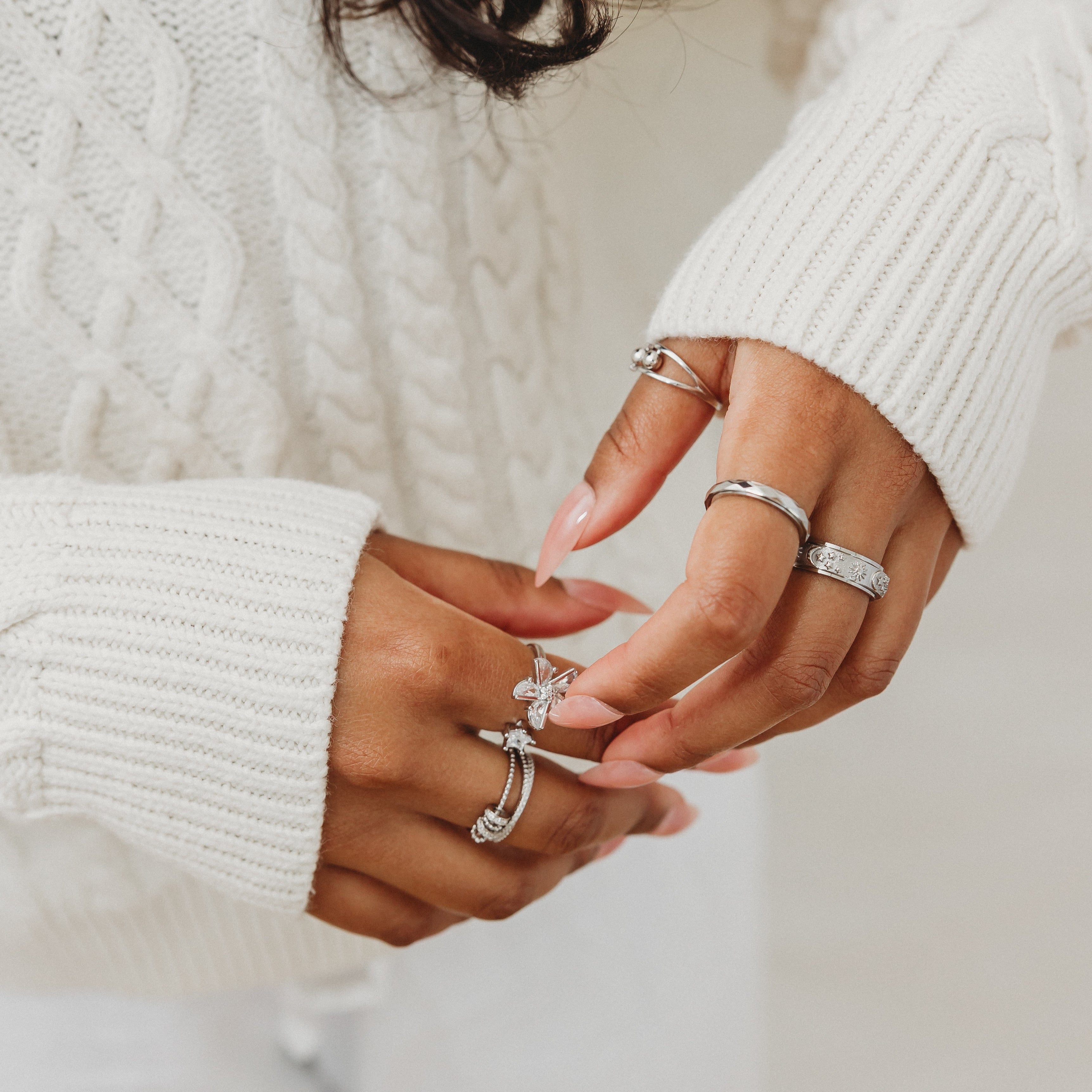 Close-up of hands wearing multiple rings with a blurred background