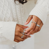 Close-up of hands wearing multiple rings with a blurred background