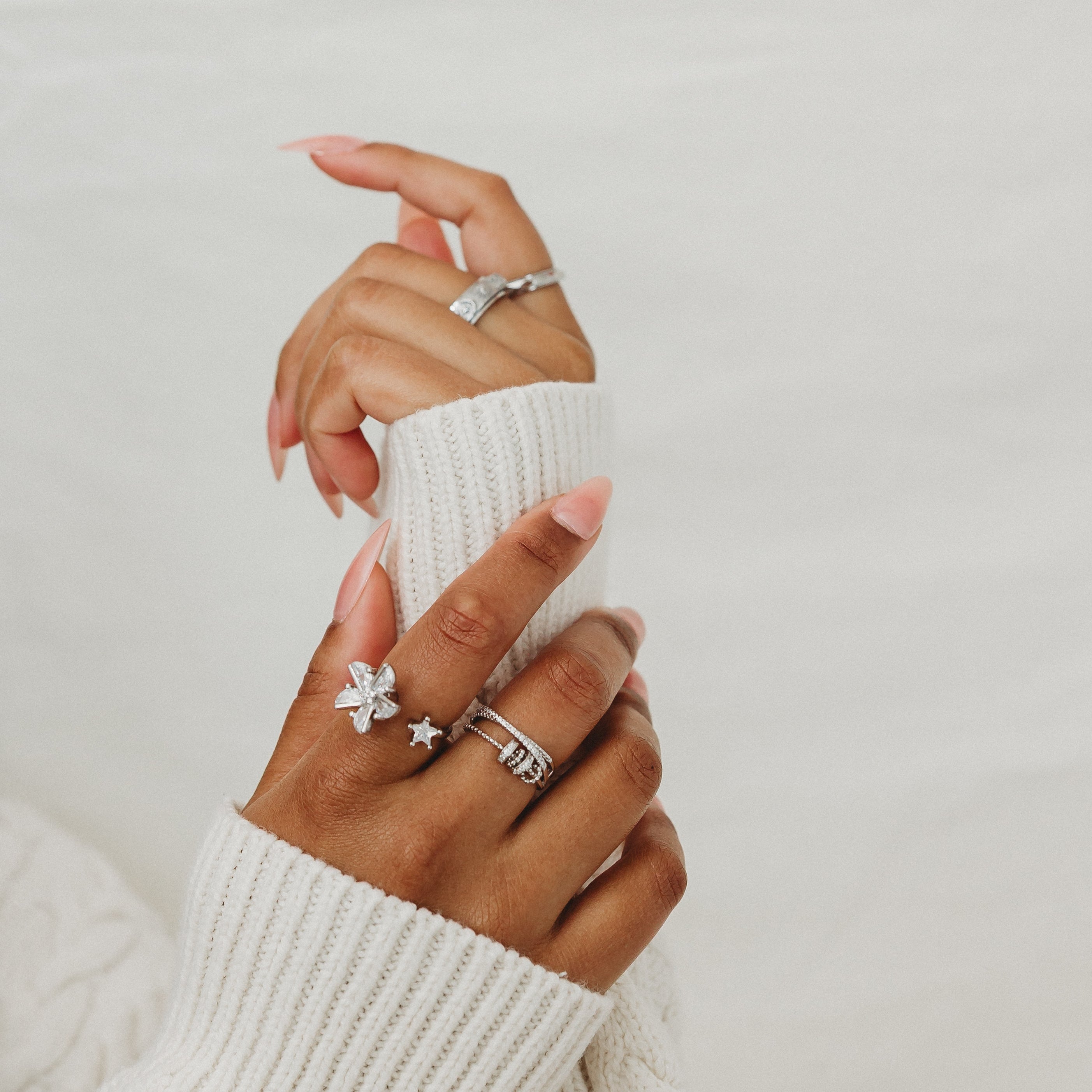 Close-up of a hand wearing multiple rings on a light background
