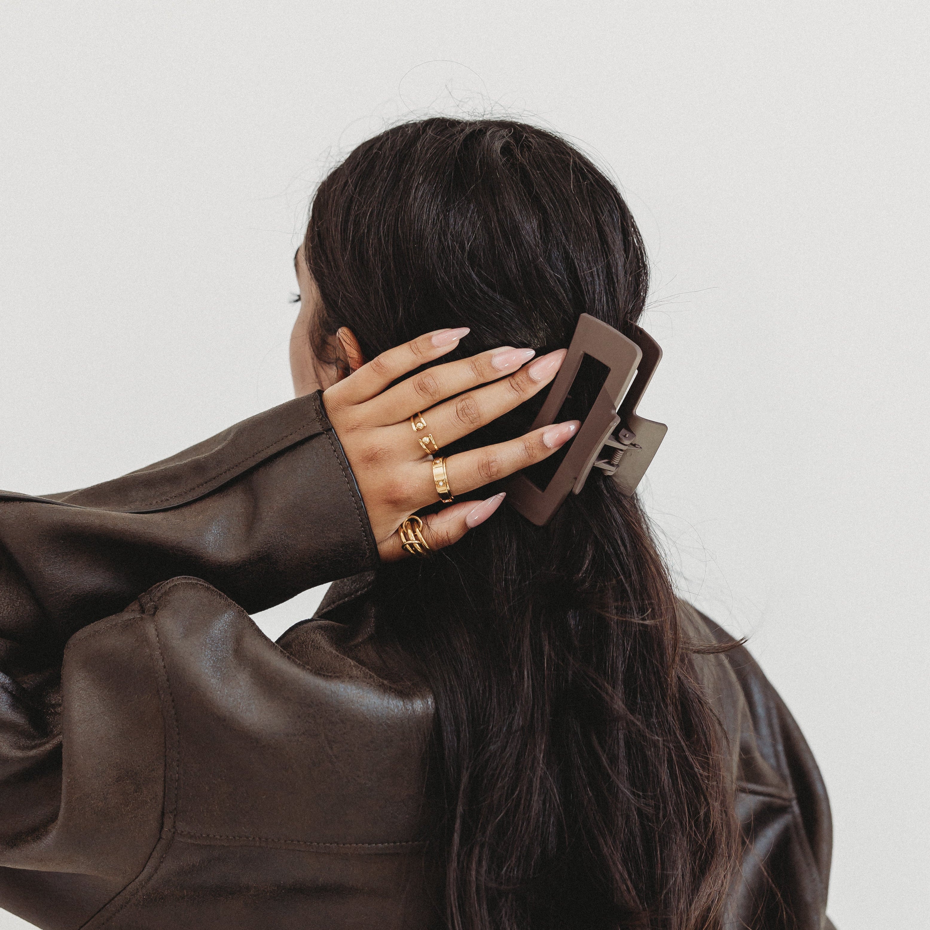 Person wearing a brown leather jacket with a plain background