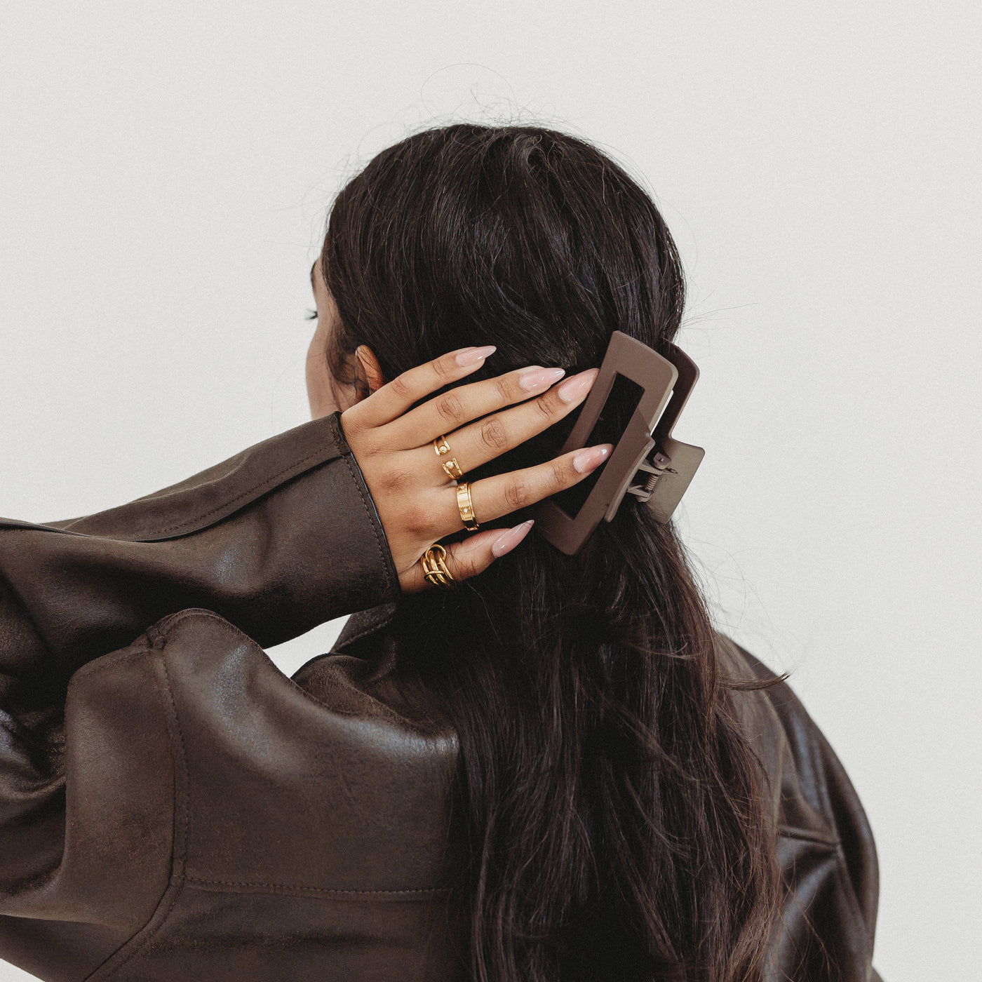 Person wearing a brown leather jacket with a plain background