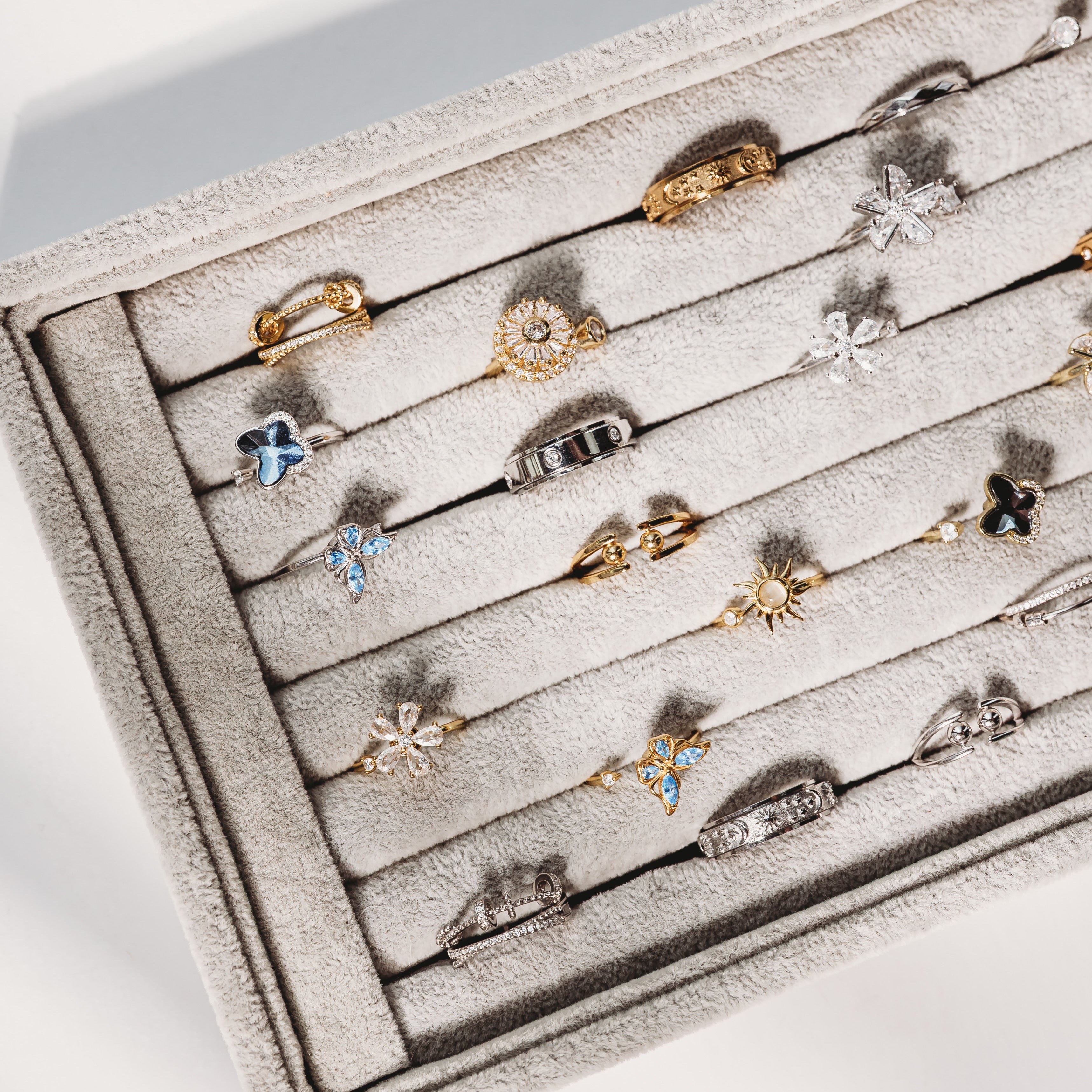 Jewelry display case with various rings on a light gray background