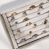 Jewelry display case with various rings on a light gray background