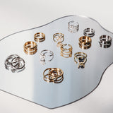 Collection of gold and silver rings on a reflective surface with a white background