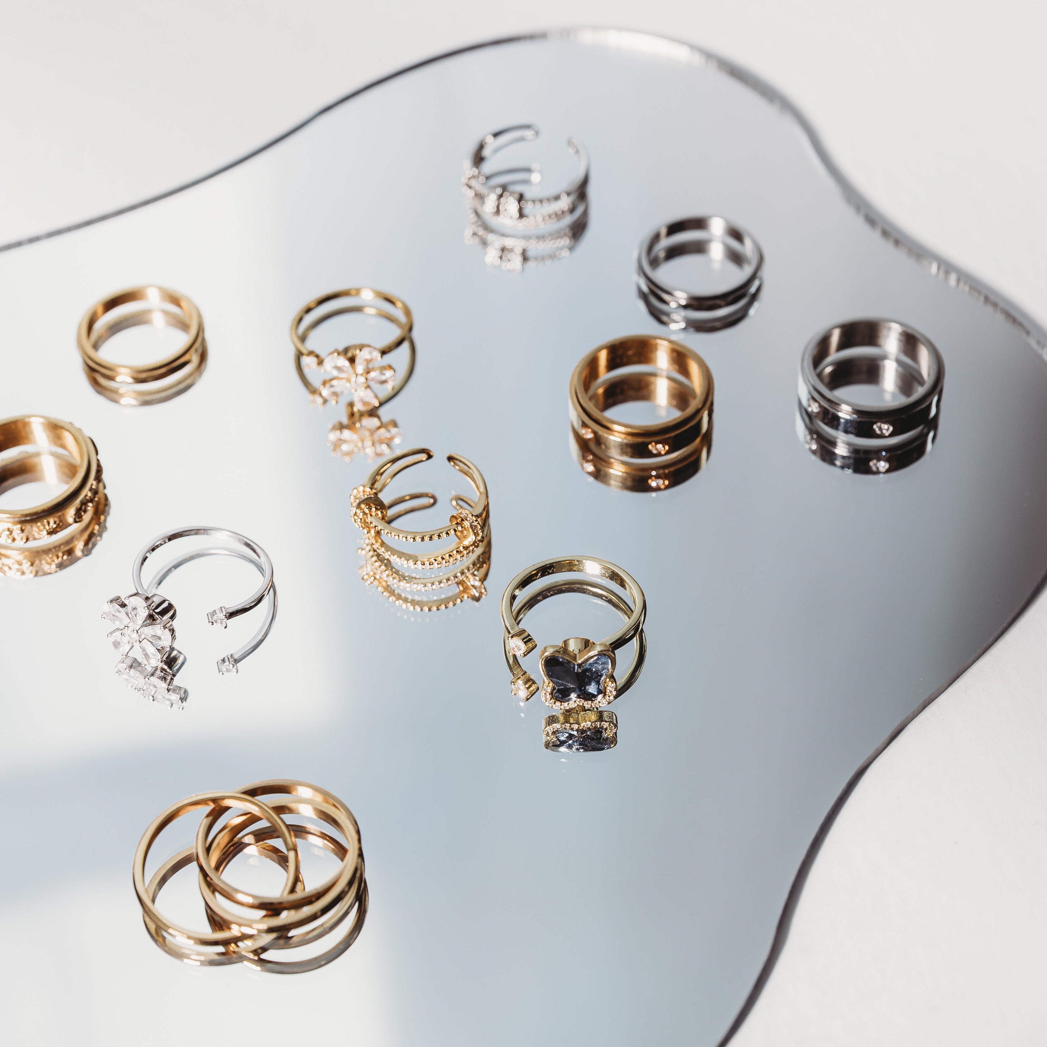 Collection of gold and silver rings on a reflective surface