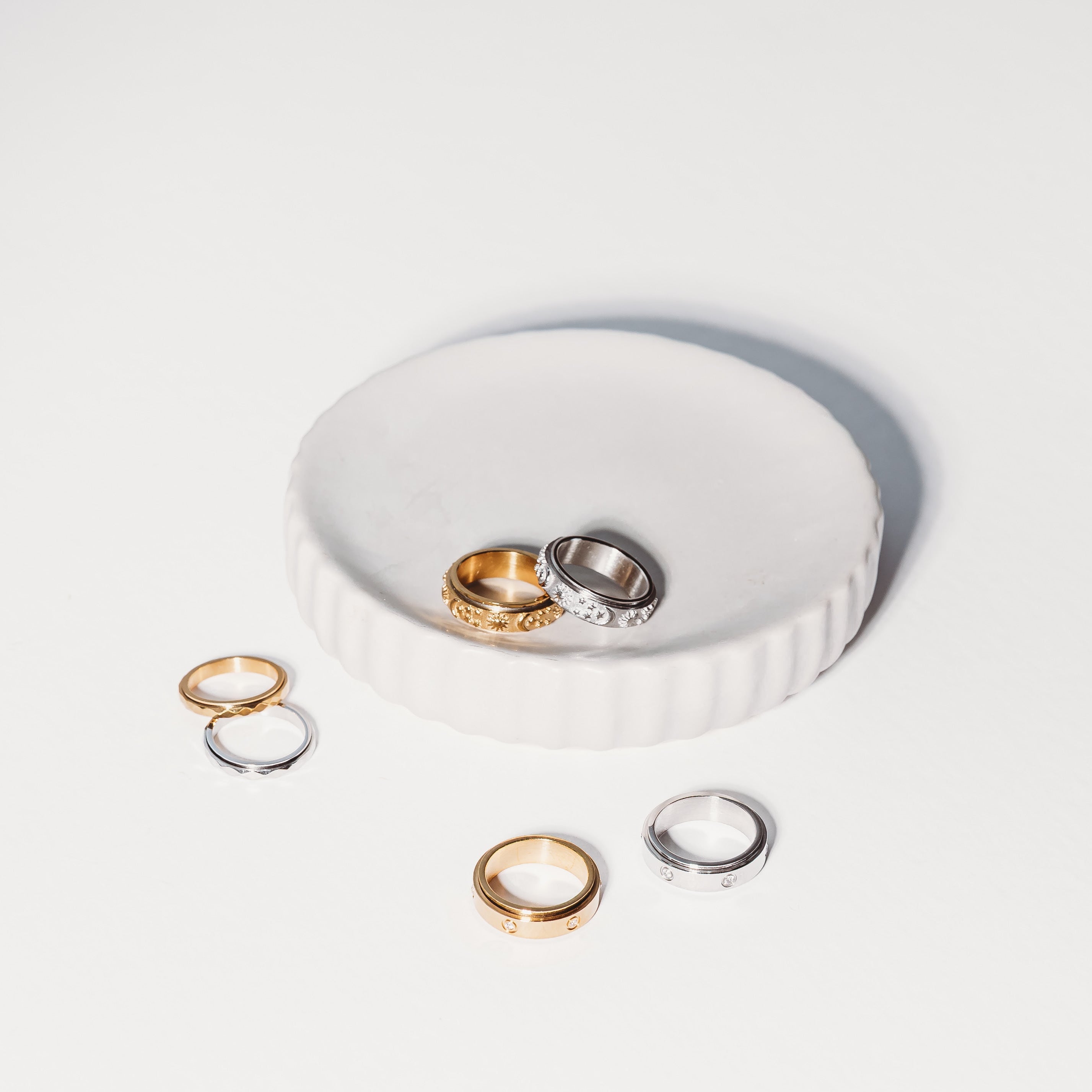 Set of gold and silver rings on a white dish with a white background