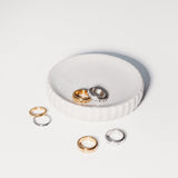 Set of gold and silver rings on a white dish with a white background