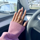 Hand with multiple rings on a steering wheel inside a car