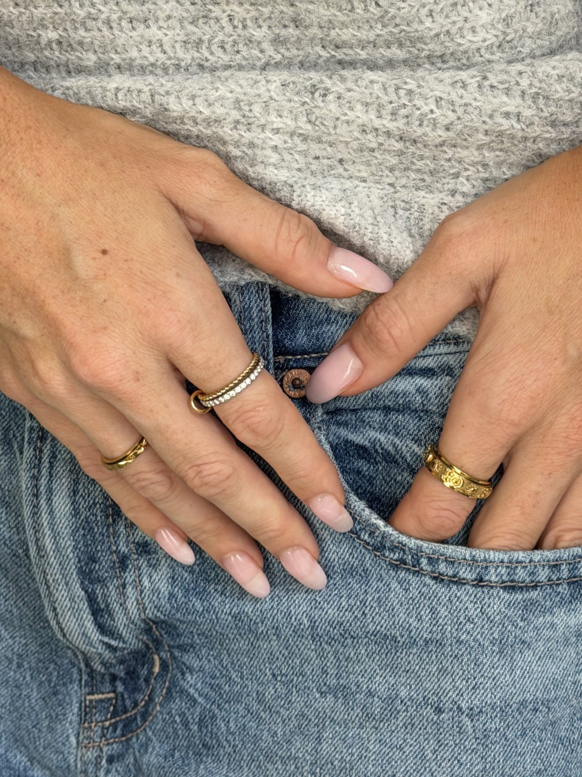 Hands in a jean pocket, gold Day and Night ring on the right hand