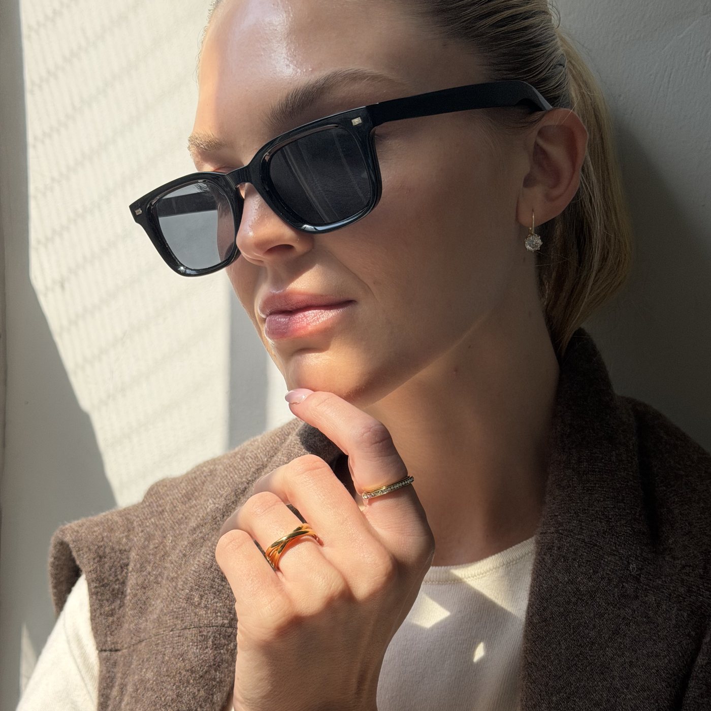 Woman in sunglasses and a knit, gold Anxi Rings on her hand in autumn light