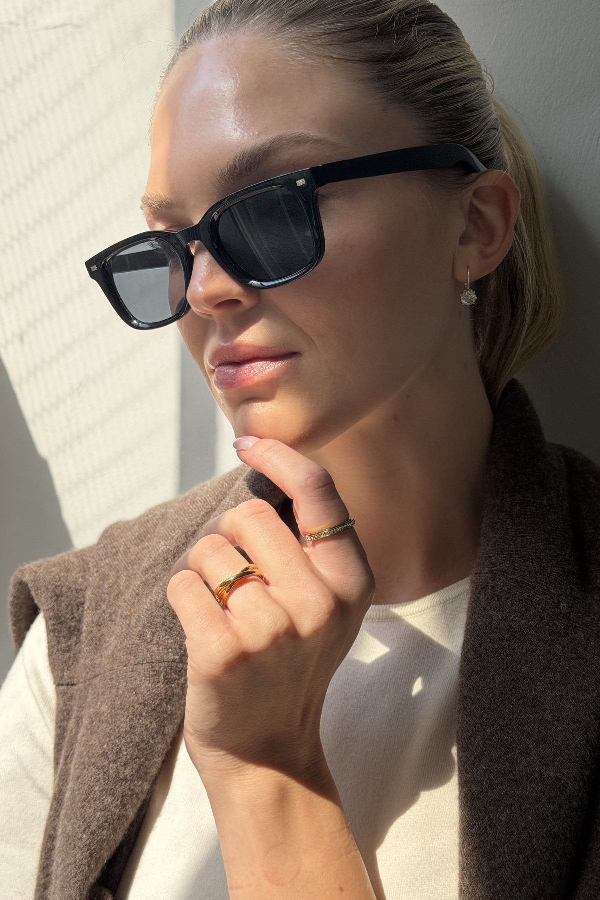 Woman in sunglasses and a knit, gold Anxi Rings on her hand in autumn light