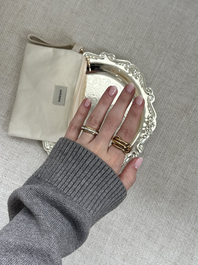 Gray knit sleeve, gold Anxi Rings on a silver tray
