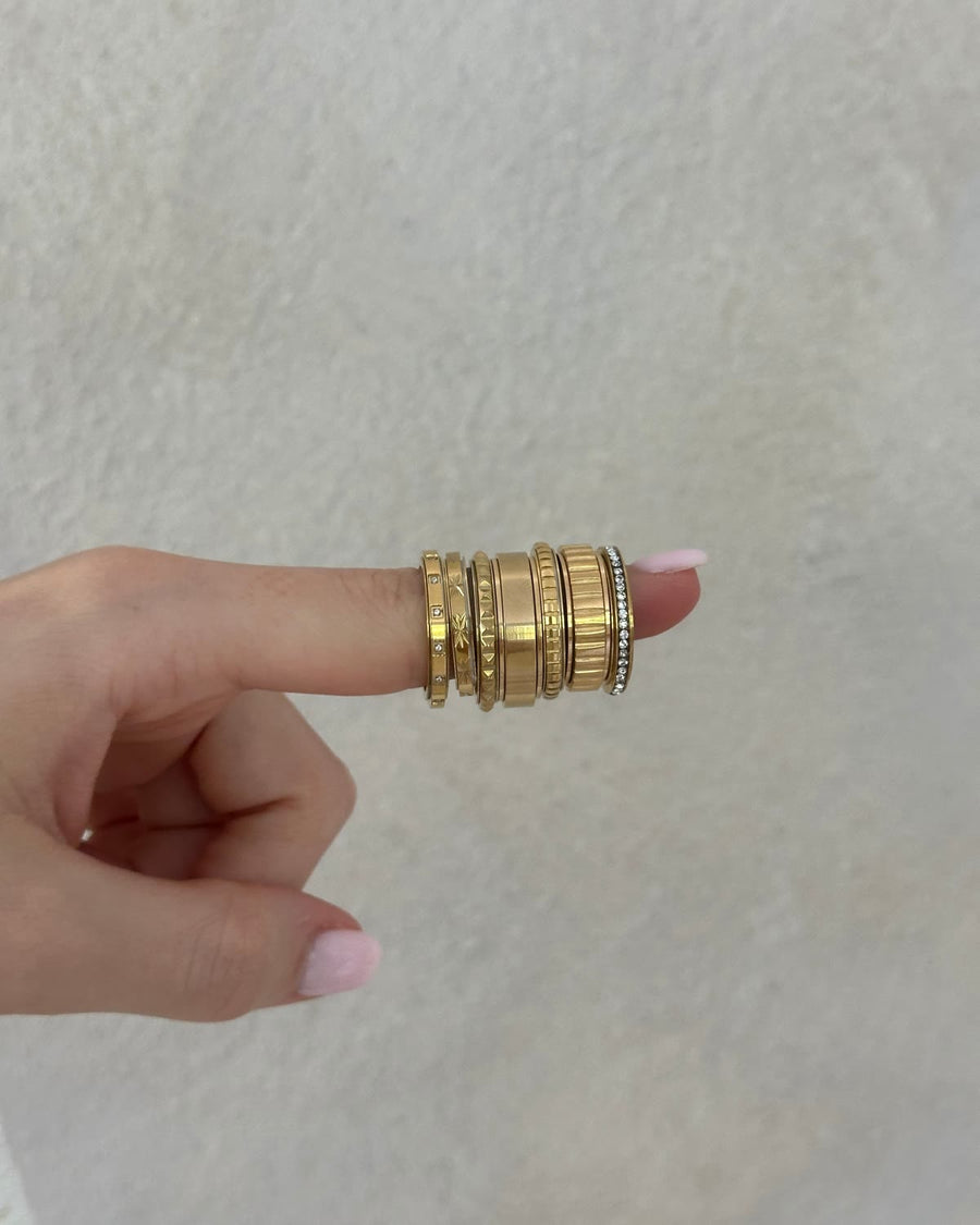 A stack of thin gold Anxi stacker fidget rings on one finger
