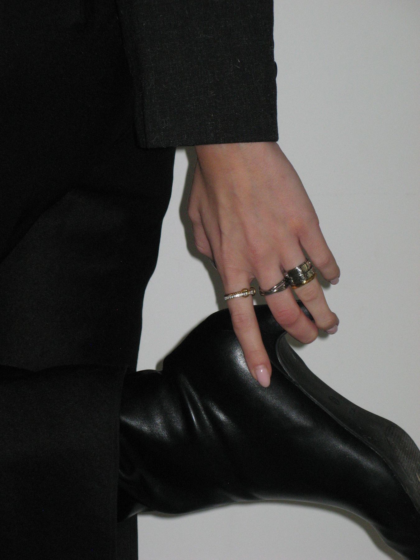 Hand wearing a stack of Anxi Rings resting on a black leather boot